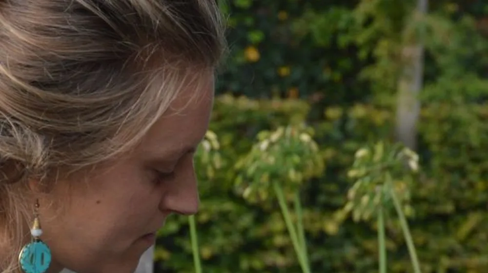 Vrouw die even stilstaat bij de bloemen in de tuin