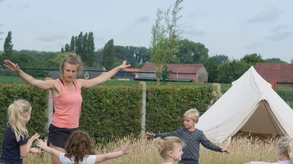 Linde doet kinderyoga met een groepje kinderen in het gras