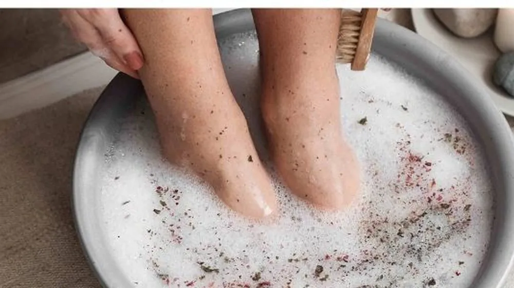 Voeten in een warm voetbad met bloemblaadjes